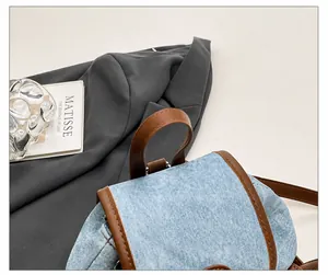 Détail d'un sac à dos en jean bleu clair avec garniture en cuir marron au style rétro