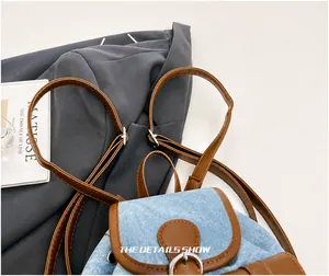 Détail des bretelles réglables avec boucles en métal argenté sur sac en jean
