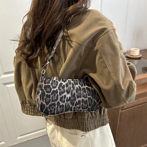 Chic leopard print underarm bag with silver hardware worn by a model in casual style