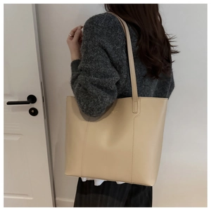 Close-up of beige leather tote bag with fine stitching and subtle gold logo detail