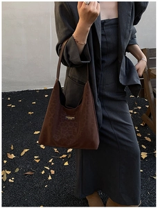 Detail of dark brown leopard print suede tote bag carried by a model in autumn scenery