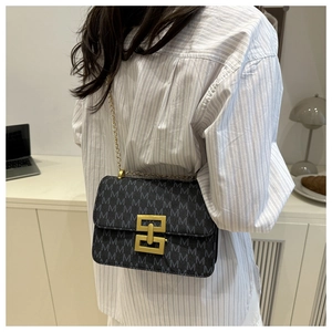 Detail view of small square shoulder bag with M-pattern print and gold chain strap
