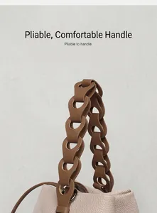 Detail of the supple brown woven leather handle on a beige pebbled leather bucket bag