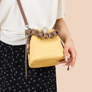 Fashionable bright yellow leather bucket bag with brown chain handle and crossbody strap