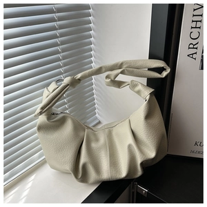 Detailed macro view of cream-colored pleated leather texture on a stylish croissant bag