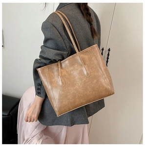 Detail view of khaki leather tote bag showing vintage marble texture on woman's shoulder