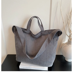 Dettaglio della borsa tote in velluto a coste grigio con texture a righe e doppi manici
