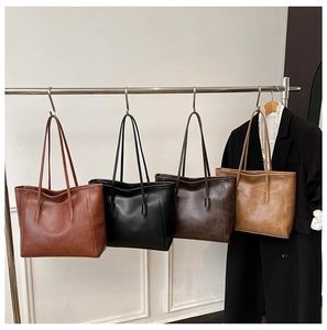 Dettaglio di borse tote in pelle PU retrò in quattro colori appese a un supporto in metallo