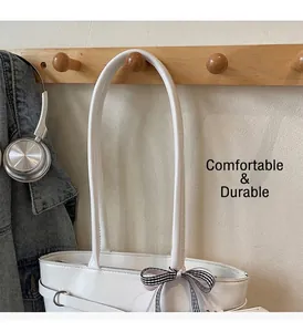 Détail du sac cabas blanc avec un nœud à carreaux noir et blanc sur la bandoulière