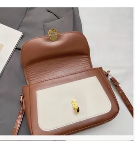 Close-up of contrast color small square bag showing golden twist lock and brown PU leather texture