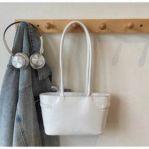 Detail of white leather bucket bag with plaid bow charm hanging on a wooden hook