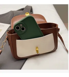 Detail view of the vintage brown and cream crossbody bag with a gold twist lock closure