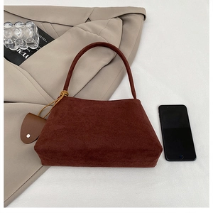 Deep brown matte suede tote bag shown with a blazer and phone for size reference