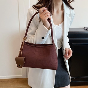 Brown suede underarm tote bag with a minimalist design and hanging leather charm