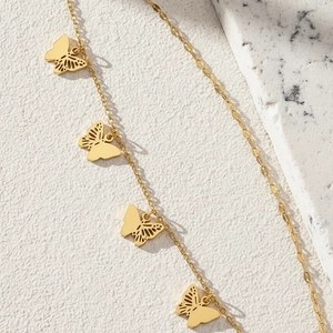 Elegant gold stainless steel anklet featuring hollow butterfly charms on a white marble base