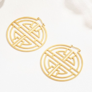 Macro detail of gold geometric hollow hoop earrings with intricate oriental pattern