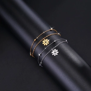 Vue macro de bracelets dorés et argentés avec pendentif marguerite et reflets brillants