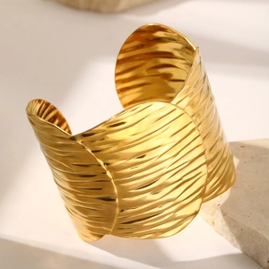 Macro detail of adjustable 18k gold plated stainless steel cuff with wave texture