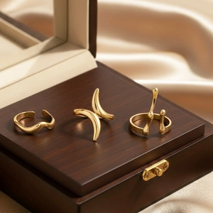 Three gold stainless steel rings with minimalist abstract wave and geometric designs