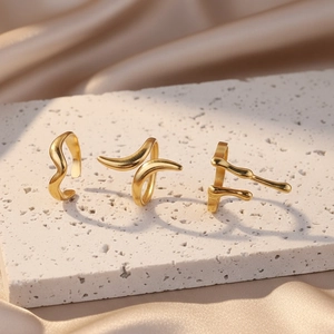 Close-up of three gold rings with irregular melted texture on stone and satin background