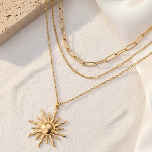 Vue détaillée du collier doré multi-rangs avec pendentif soleil et maille trombone