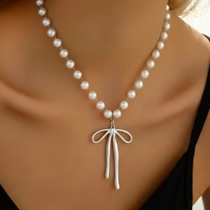Elegante Edelstahl-Perlenkette mit silbernem Schleifenanhänger am Hals eines Models