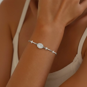 Silver stainless steel religious bracelet with cross and oval icon charms on female wrist