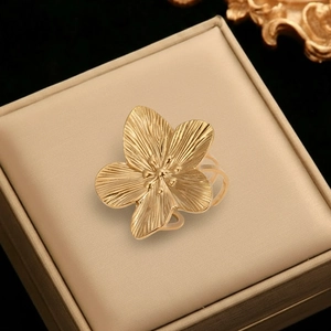 Detail of golden flower ring with brushed metal texture in a beige jewelry box