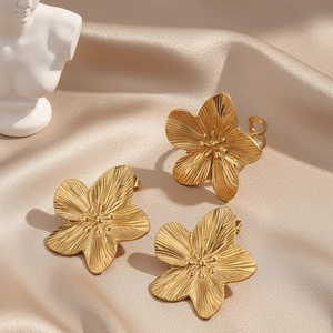 Elegant gold flower jewelry set with textured petals on a satin champagne backdrop