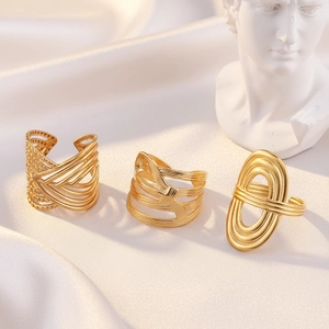 Detailed view of three gold geometric stainless steel rings on white silk with a statue