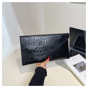 Close-up of black crocodile pattern envelope clutch bag with high-gloss leather texture