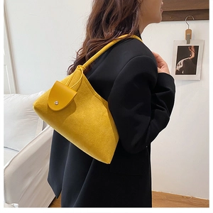 Close-up of vibrant yellow felt shoulder bag with metal buckle on a black blazer