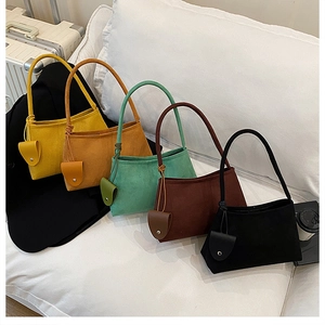 Variety of matte suede tote bags in yellow, brown, and green on a white sofa setting