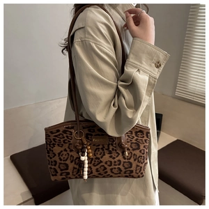Close-up of leopard print suede bag with FASHION label and beaded charm detail