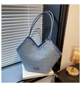Detail of blue tweed tote bag showing gold thread texture and V-shaped opening