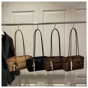 Detail of four chic tote bags with tassel charms hanging on a white vintage door
