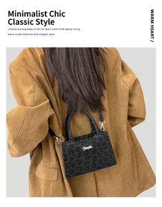 Femme portant un mini cabas noir en daim à imprimé léopard avec logo argenté