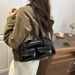 Glossy black patent leather Boston bag with front pockets shown on a model