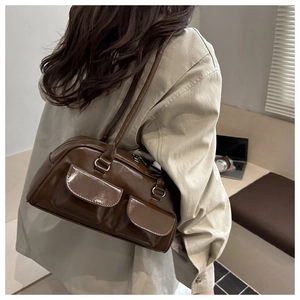 Dettaglio di una borsa a spalla marrone scuro lucida con doppie tasche frontali vintage