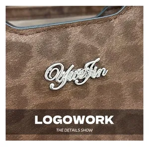 Vue macro de la texture en daim marron foncé et logo YueJin en métal argenté poli
