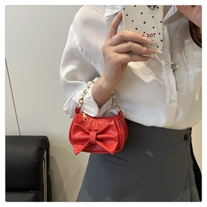 Detailed view of mini red handbag featuring a large bow and elegant pearl handle