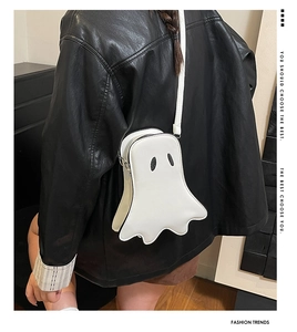 Rear view of a stylish white ghost-shaped crossbody bag worn over a black leather jacket