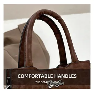 Détail des poignées arrondies et du logo en métal argenté sur le sac en daim marron