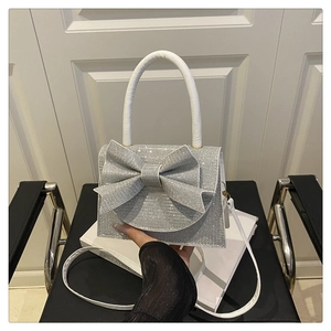 Detail of silver rhinestone bow evening bag showing shimmering crystal texture and handle