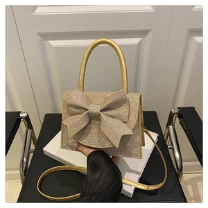 Close-up of golden mini handbag with sparkling rhinestones and a large decorative bow