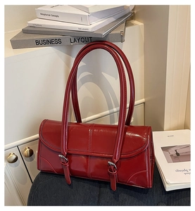 Detail showing high-gloss deep red faux leather texture and vintage buckle on baguette bag