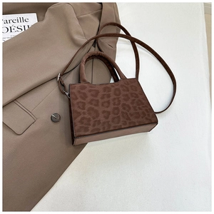 Gros plan du sac bandoulière léopard en suédine avec bandoulière réglable sur un manteau