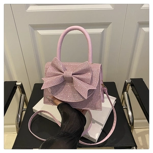 Detail of pink rhinestone handbag featuring a large bow and detachable shoulder strap