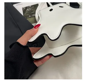 Close-up of white ghost shaped bag showing detailed black stitching and leather texture