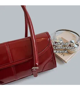 Burgundy oil wax leather baguette bag next to a laptop and headphones on a desk